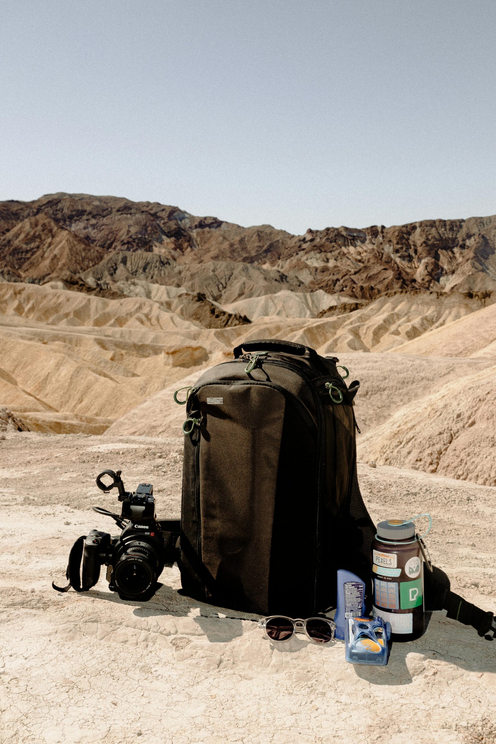 A backpack with camera gear on a desert landscape, ideal for outdoor photography enthusiasts.
