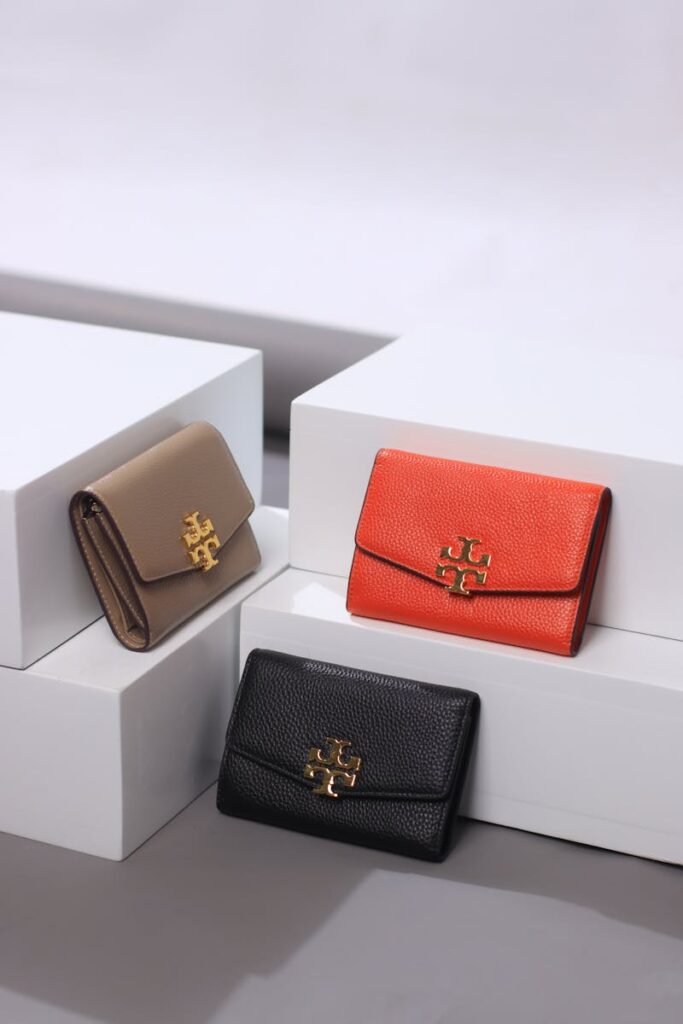 Three leather wallets elegantly displayed on white platforms in a professional studio setting.